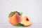 Light soft summer fruit background - ripe peach with bright fresh piece and green leaf on white wood table, copy space.