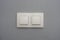A light switch, a plastic mechanical switch of white color installed on a light gray wall in the room