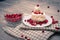 On a light tabletop on a linen napkin in a saucer cake with whipped cream with fresh berries, a bowl with red berries