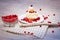 On a light tabletop on a linen napkin in a saucer cake with whipped cream with fresh berries, a bowl with red berries