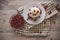 On a light tabletop on a linen napkin in a saucer cake with whipped cream with fresh berries, a bowl with red berries