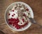 Light and tasty Breakfast with homemade cottage cheese, seeds and berry jam in a white deep plate with a spoon on a rough wooden