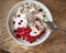 Light and tasty Breakfast with homemade cottage cheese, seeds and berry jam in a white deep plate with a spoon on a rough wooden