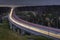 Light trails on four lane highway, crosses the night forest.