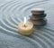 Light warm candle and stone on sand