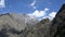 Light white clouds float over the top of a high, rugged mountains with snow remnants. Caucasus. Georgia.