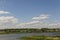 Light white clouds in the warm summer sky over village with small houses far away in the fields. Travelling. People living