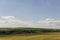 Light white clouds in the warm summer sky over village with small houses far away in the fields. Travelling. People living