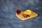 Light wooden board with a glass of cognac, chocolate pieces and lemon wedges on a gray background