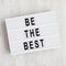 Lightbox with `Be the best` words on a white wooden background. Flat lay, overhead, top view, from above