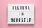 Lightbox with motivational quote Believe in Yourself on pink background, top view