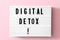 Lightbox with phrase DIGITAL DETOX on pink background, top view