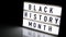 Lightbox with text BLACK HISTORY MONTH on dark black background with mirror reflection. Message historical event. 4k Video. Zoom i