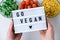 Lightbox with text GO VEGAN Three Bowls of frozen vegetables food of yellow corn, green beans, red tomatoes. Colors of