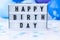 Lightbox with text HAPPY BIRTHDAY on Abstract defocused blurred festive background for holiday. Blue ballons and confetti.