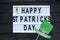 Lightbox with title Happy st Patrick Day and photobooth bow tie beard on wooden sticks on black wooden background.