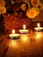 Lighted candles and a wicker basket with a pumpkin and flowers in the background