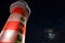 Lighted lighthouse against dark sky by full moon low-angle