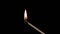 A lighted match burns with smoke on a black background. Concept of slow-motion video with fire. The hand lights a match.