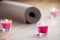 Lighted pink candle and rolled brown yoga, pilates mat on the fl