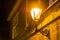 Lighted street lantern on the wall of a house at night, city scenery in the evening, vintage decoration