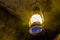 Lighted vintage lantern hanging on the roof of a cave, nostalgic mining equipment