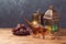 Lightened lantern, tea cups and dates on wooden table over blackboard background. Ramadan kareem holiday celebration