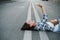 Lighthearted woman lying on an asphalt road, talking on her phone. Side view.