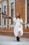 Lighthearted young woman walking down the street in a white fluffy dress