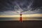 a lighthouse on the beach with the sun setting behind it