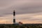 Lighthouse beacon shining as storm clouds streak across the sky.