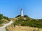 the lighthouse at the bottom of a grassy hill on a sunny day