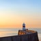 Lighthouse on breakwater wall during sunrise