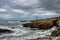 Lighthouse with cloudy stormy sky and rough coastline