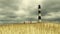 Lighthouse with Grassy Sand Dunes on a Cloudy Day with Two People in Hazmat Suits