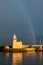 The lighthouse at Howth Harbour in County Dublin bathed in sunlight under a rainbow in front of a stormy sky