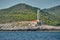 The lighthouse on the island in Croatia nearby Vis at sunset, a rocky coast, ladder to a beacon, a small cape