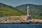 The lighthouse on the island in Croatia nearby Vis at sunset, a rocky coast, ladder to a beacon, a small cape