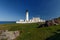 Lighthouse and keepers house on grassy hillside along the sea