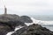 Lighthouse next to Nato base in Stokksnes peninsula next to the city of Hofn in Iceland. Waves crash ashore with overcast sky