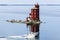 Lighthouse in Norway with motorboat in front, red wooden lighthouse