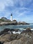 Lighthouse on the ocean in Portland Maine with rocks on the shore