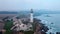 Lighthouse on the ocean shore in rainy coastal weather.