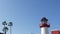 Lighthouse, palm trees and blue sky. Red and white beacon. Waterfront harbor village. California USA