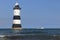 The lighthouse at Penmon Point Anglesey with motor boat