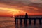 Lighthouse pier and setting sun over the water.