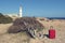 Lighthouse and red suitcase on a rocky shore at Cap de Ses Salines