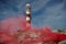 A lighthouse on a rocky coast in Cancun with a red smoke screen. Mexico.