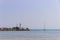 Lighthouse and sail boat at summer shiny day