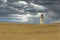 Lighthouse on a sand dune on background of gloomy clouds